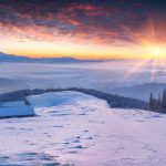 雪に覆われた山々のカラフルな冬の日の出の風景
